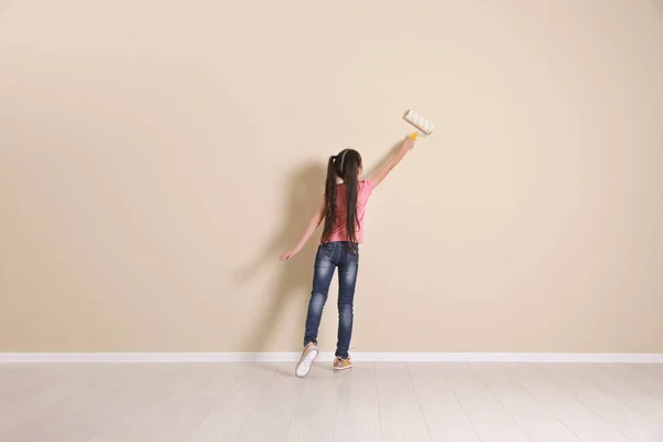 Child painting color wall with roller brush