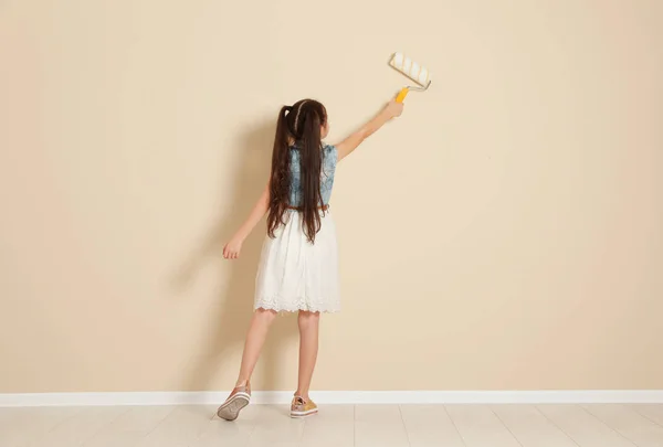 Child painting color wall with roller brush. Space for text