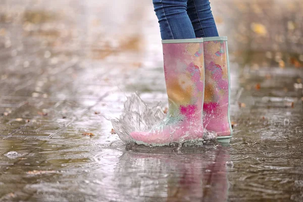 ゴムを身に着けている女性の足に焦点を当てるの雨の後水たまりの中で水しぶきブーツします 秋の散歩 — ストック写真