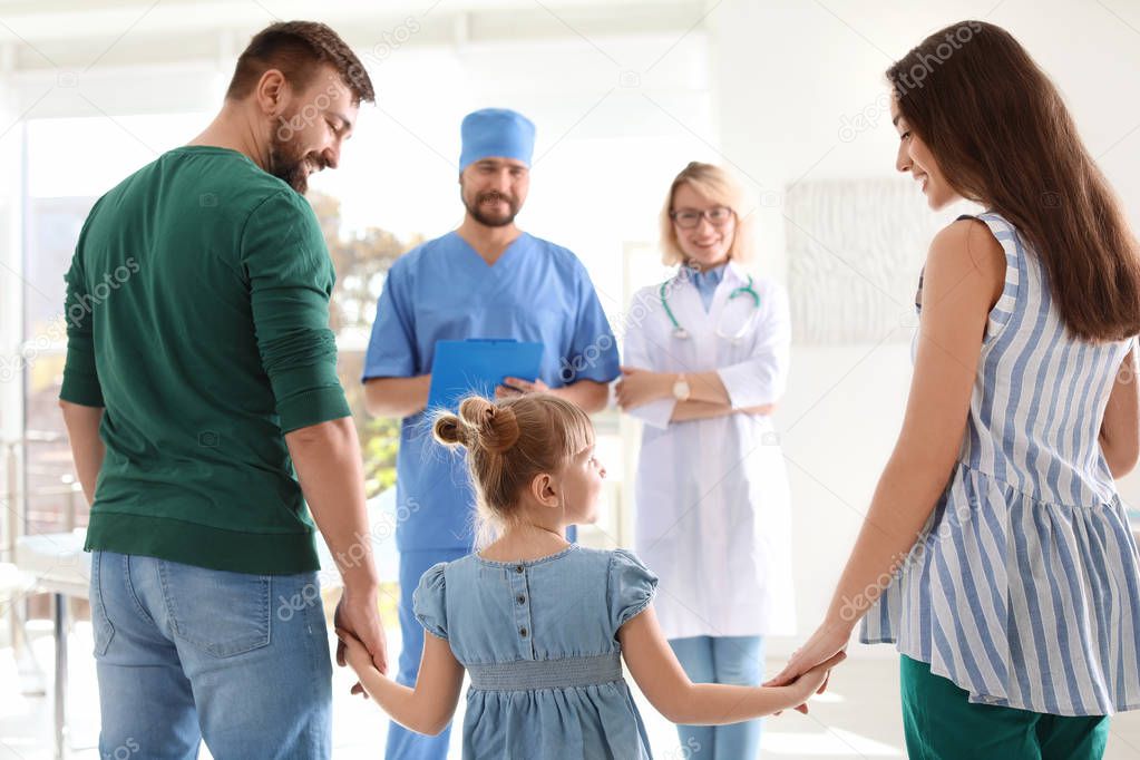 Little girl with parents visiting children's doctors in hospital