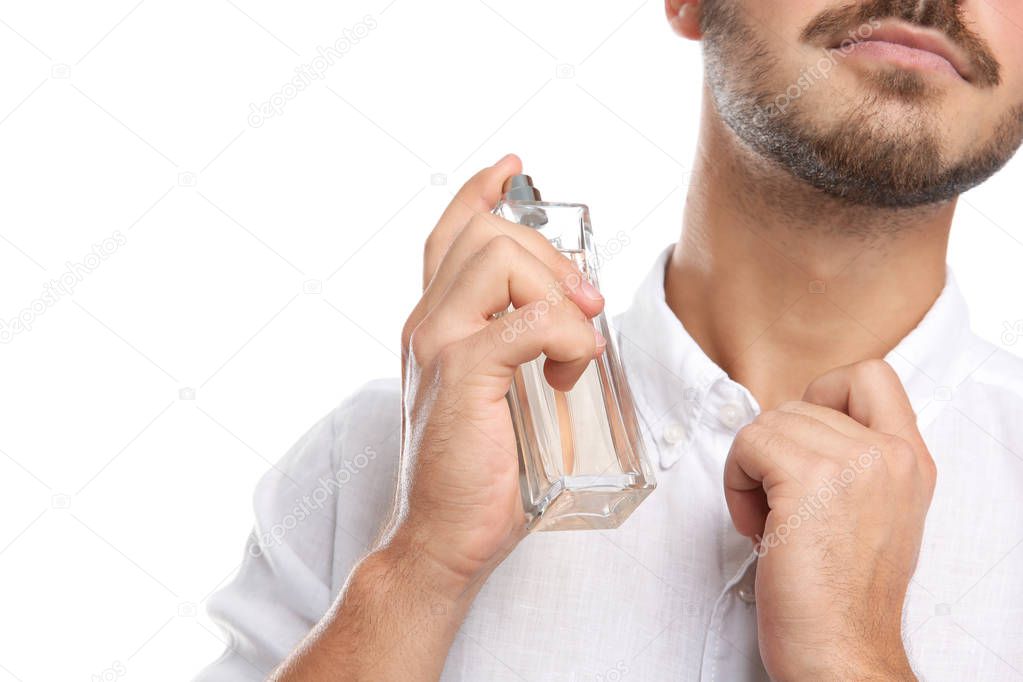 Young man applying perfume on white background, closeup