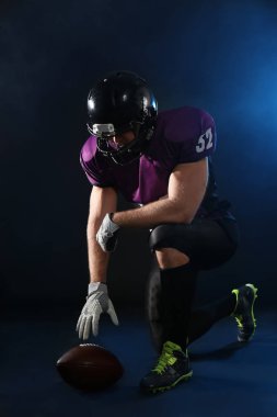 Koyu arka plan üzerinde topu ile Amerikan futbolu oyuncusu