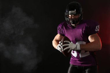 Amerikan futbolu oyuncusu topa koyu arka plan ile. Metin için yer