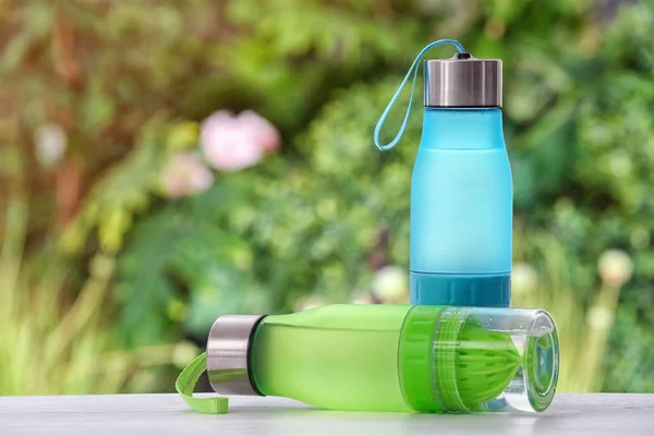 Sports water bottles on table against blurred background. Space for text