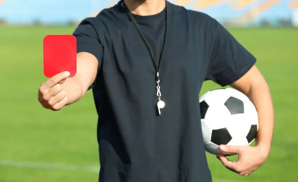 Football referee showing red card at stadium, closeup