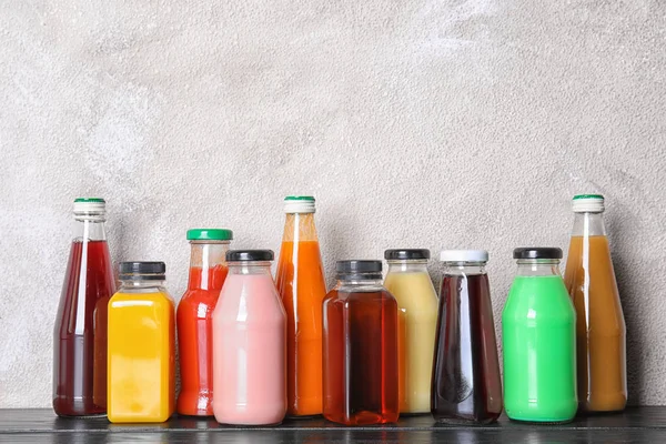 Garrafas Com Diferentes Bebidas Mesa Contra Fundo Cor — Fotografia de Stock