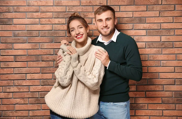 在砖墙附近穿着保暖毛衣的年轻夫妇 — 图库照片