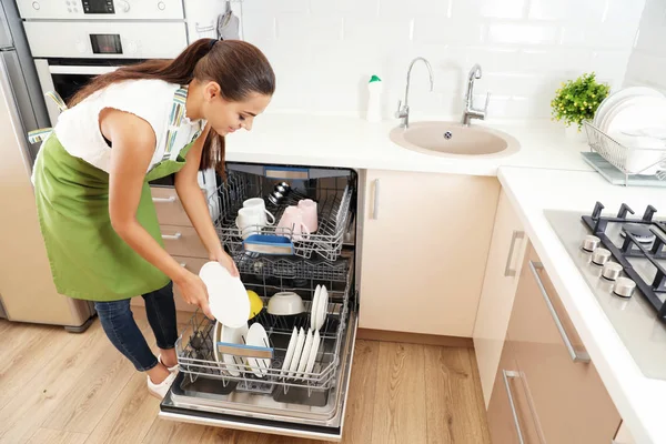 美しい若い女性ロードは キッチンの食器洗い機 クリーニングの雑用 ストック写真
