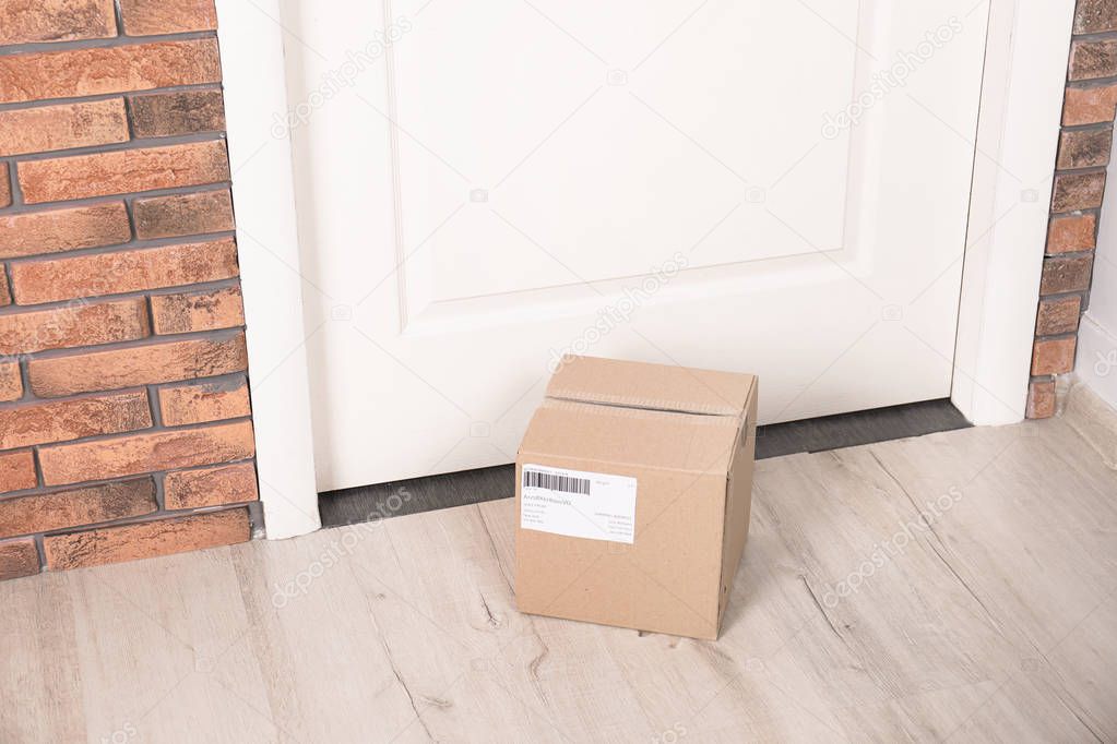 Cardboard parcel box on floor near apartment entrance. Mockup for design