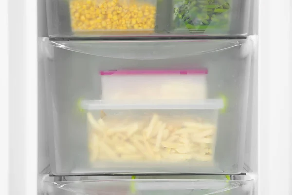 Containers with frozen vegetables in refrigerator, closeup