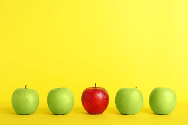 Fila Manzanas Verdes Con Una Roja Sobre Fondo Color Diferente — Foto de Stock