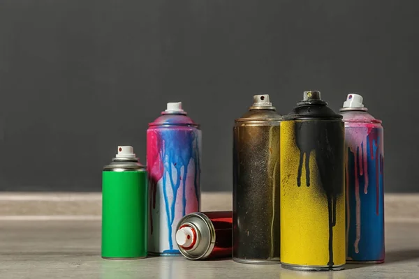 Used cans of spray paint on floor indoors