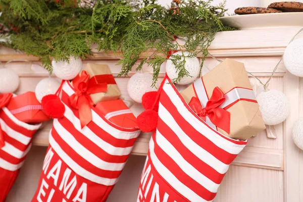 Red Christmas stockings hanging on decorated fireplace, indoors. Festive interior — Stock Photo, Image