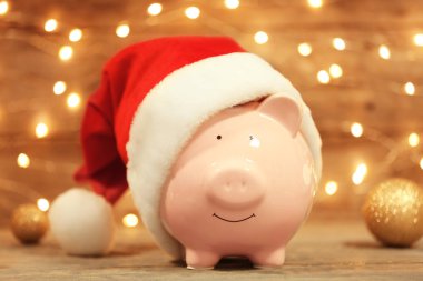 Bulanık Noel ışıkları karşı masada Noel Baba şapkası ile şirin kumbara