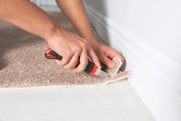 Man Cutting New Carpet Flooring Indoors Close Seup — стоковое фото