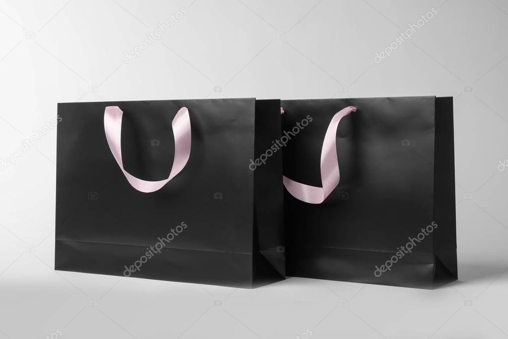 Paper shopping bags with ribbon handles on white background. Mockup for design