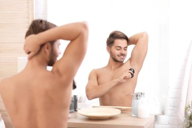 Yakışıklı genç adam banyoda deodorant uygulamak