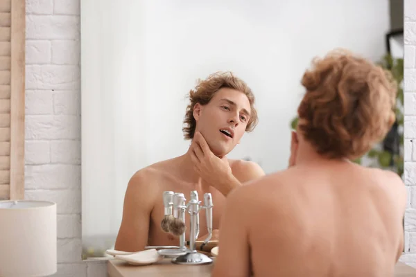 家庭で髭剃り後に鏡で見ている若者 — ストック写真