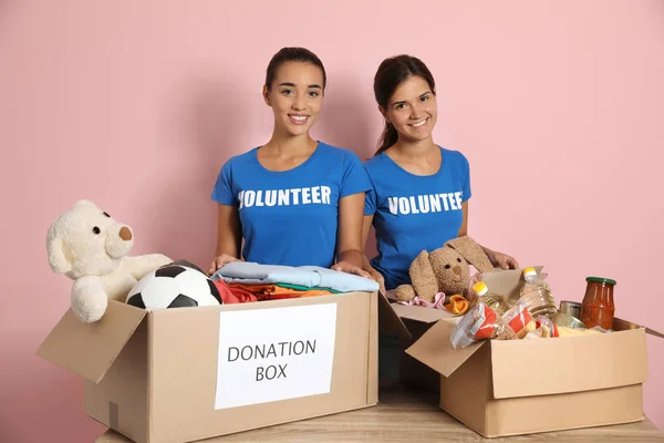 Jóvenes Voluntarios Recogiendo Donaciones Mesa Sobre Fondo Color — Foto de Stock