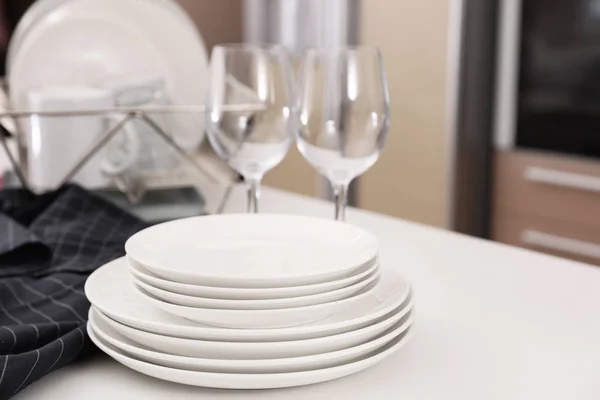 Stack of clean dishes and glasses on table in kitchen