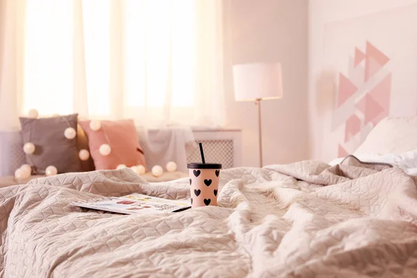 自宅のベッドの上に雑誌でホットド リンクのカップ — ストック写真