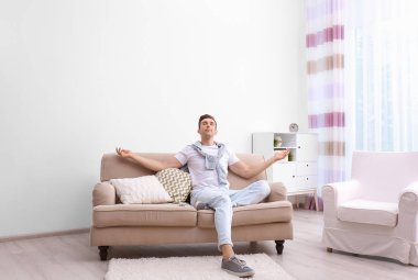 Klima altında evde oturan mutlu genç adam