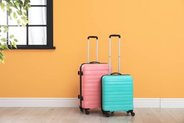 Zemin rengi duvarının yakınında seyahat bavul dolu