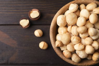 Kabuklu organik Macadamia fıstığı ve ahşap arka plan, üstten görünüm üzerinde metin için yer ile kase