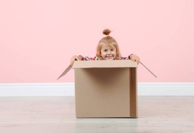 Sevimli küçük kız renk duvar kapalı yakınındaki karton kutu ile oynarken