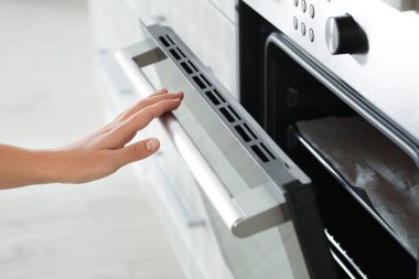 Genç kadın elektrikli fırın mutfak, closeup açma