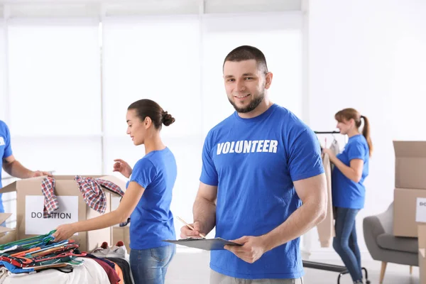 Hombre Voluntario Con Portapapeles Listando Donaciones Interiores — Foto de Stock