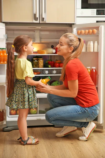年轻的母女和在冰箱附近的果汁在家 — 图库照片