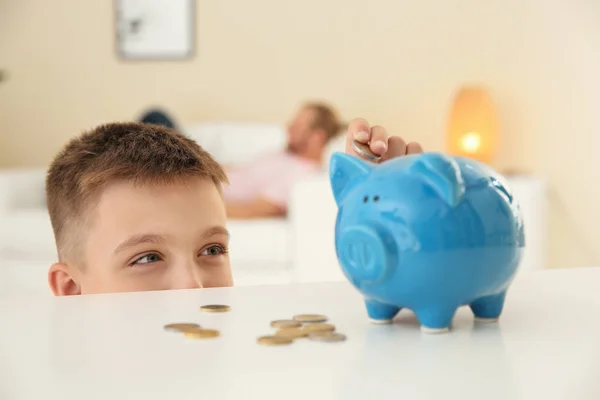 Jongetje Munt Ingebruikneming Piggy Bank Tafel Binnenshuis — Stockfoto