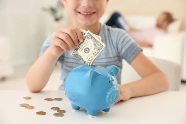 Kleine Jongen Geld Steken Piggy Bank Tafel Binnenshuis — Stockfoto