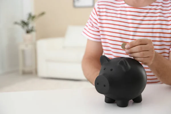 Man Putting Coin Piggy Bank Table Blurred Background Closeup Space — Stock Photo, Image