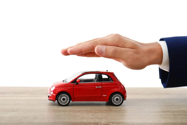 白い背景に クローズ アップ テーブルにおもちゃの車の上の手を握って保険エージェント — ストック写真