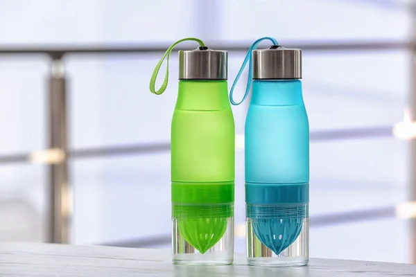 Sports water bottles on table against blurred background. Space for text