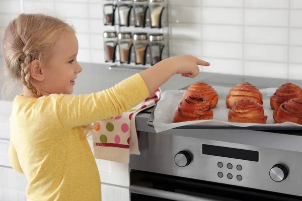 Little girl with tray of oven baked buns in kitchen