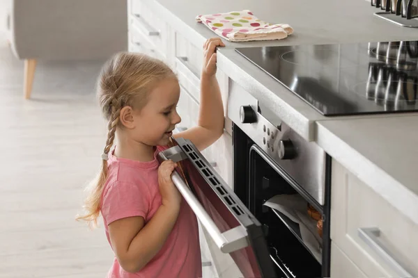 小女孩打开烤箱 而烘烤在厨房里 — 图库照片