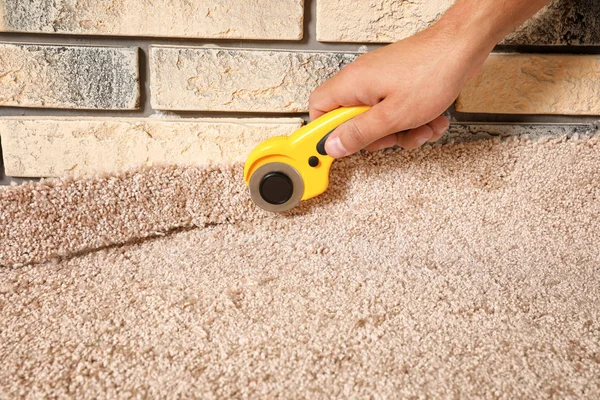 Man Cutting New Carpet Flooring Indoors Close Seup — стоковое фото