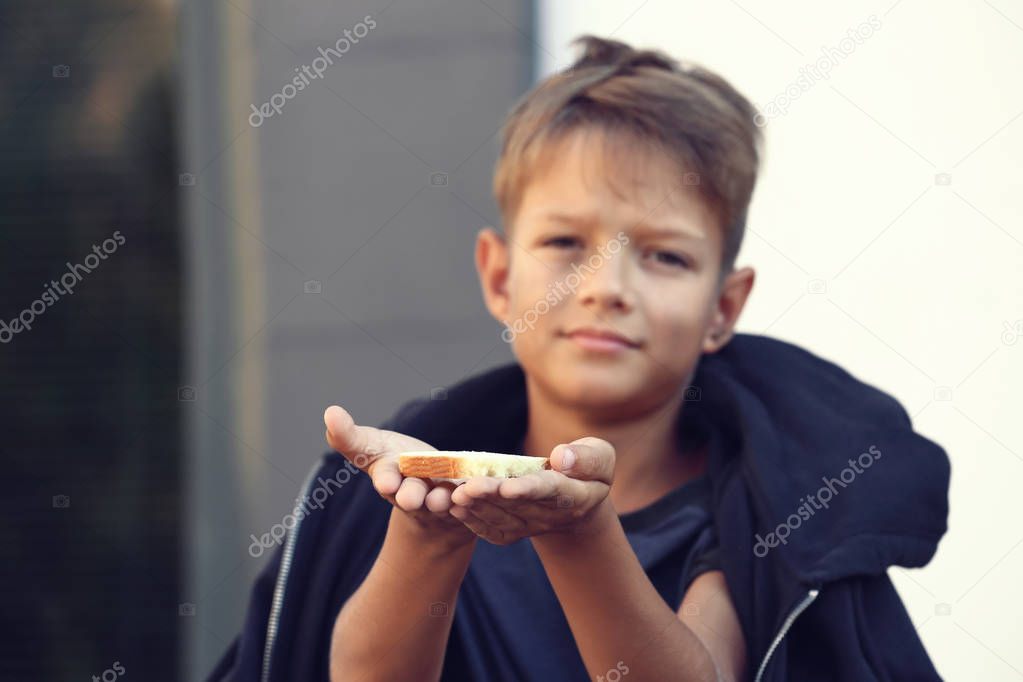 Poor little boy with bread on city street