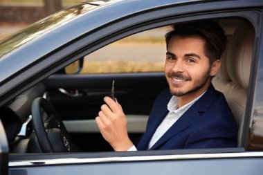 Arabanın anahtarını otomatik olarak tutan genç adam. Lisans test sürüş