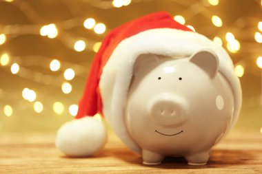 Bulanık Noel ışıkları karşı masada Noel Baba şapkası ile Piggy banka. Metin için yer