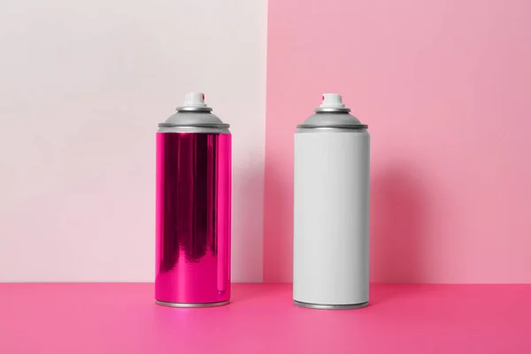 Cans of different spray paints on color background