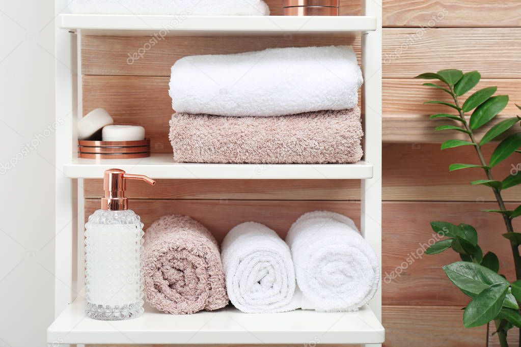 Towels, toiletries and soap dispenser on shelves in bathroom