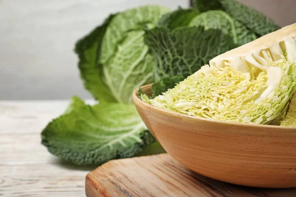 Bowl with cut savoy cabbage on table, closeup. Space for text