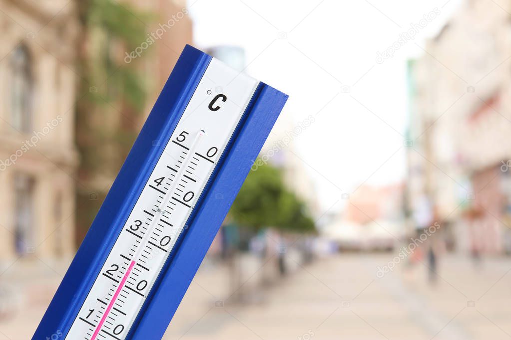 High temperature on thermometer and city view