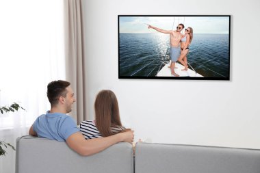 Genç çift evde kanepede televizyon izlerken