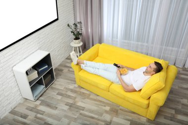 TV izlerken, yemek genç adam kanepede evde, görünümü fişleri. Mockup tasarım için