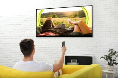 Genç adam evde kanepede televizyon izlerken